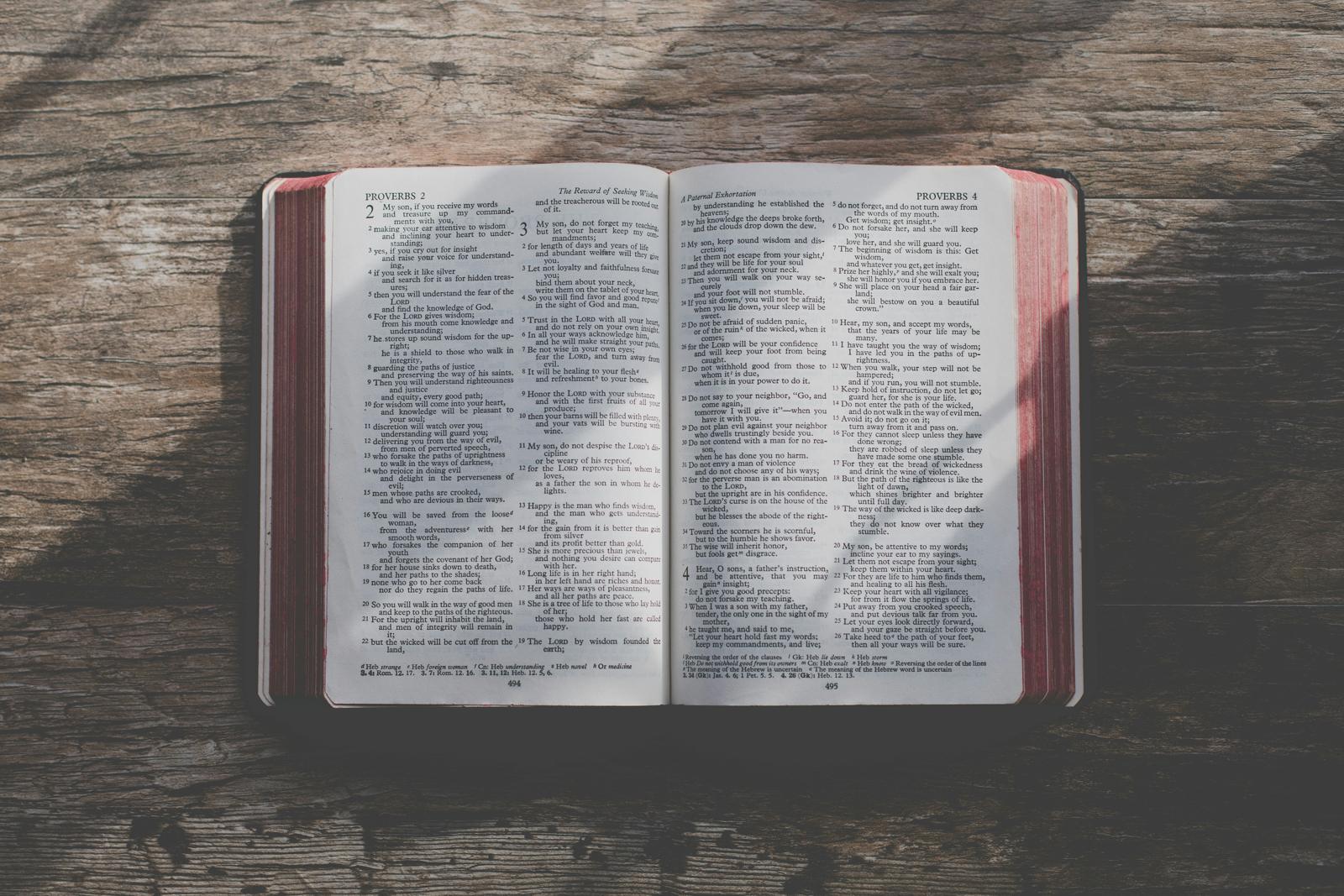 An open Bible on a weathered wooden table