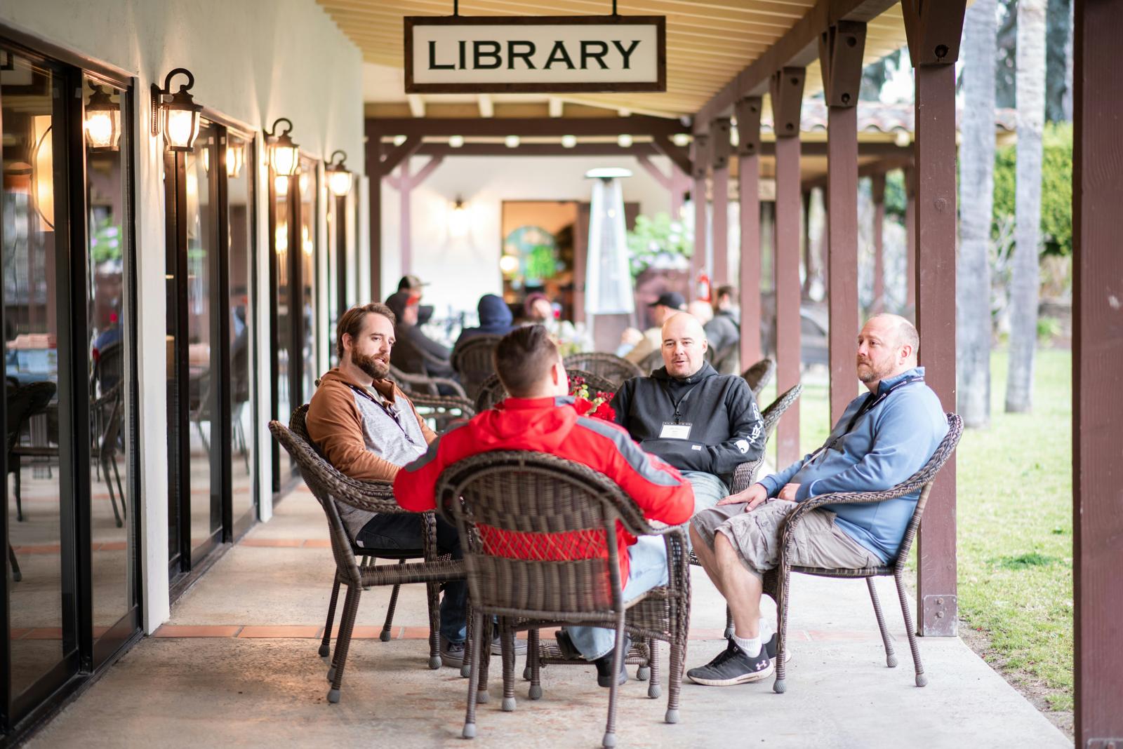 Men gathered in conversation on a covered porch