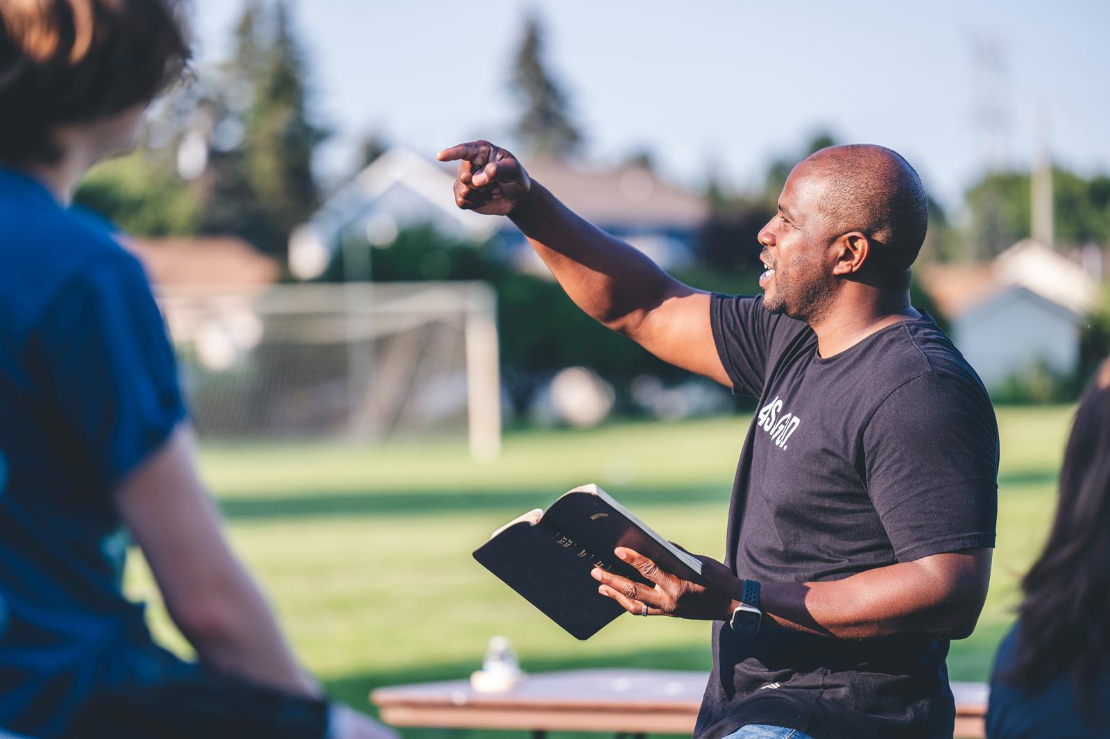 A mentor teaching from the Bible outdoors