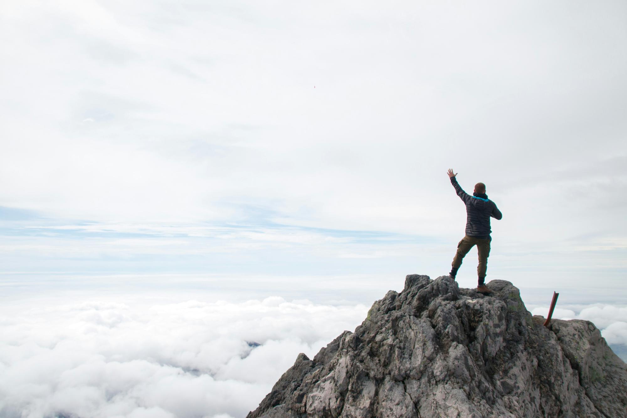 A man standing on a summit above the clouds